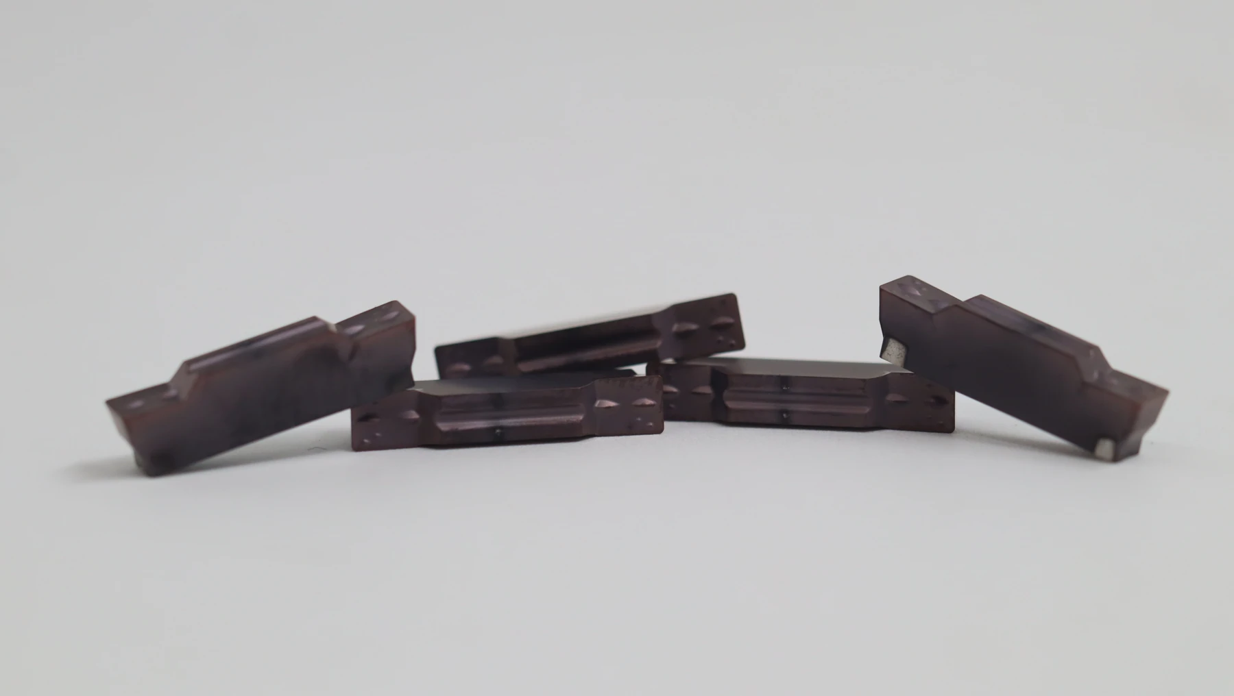 Two dark grooving inserts propped against each other, the ground flute running the length of each