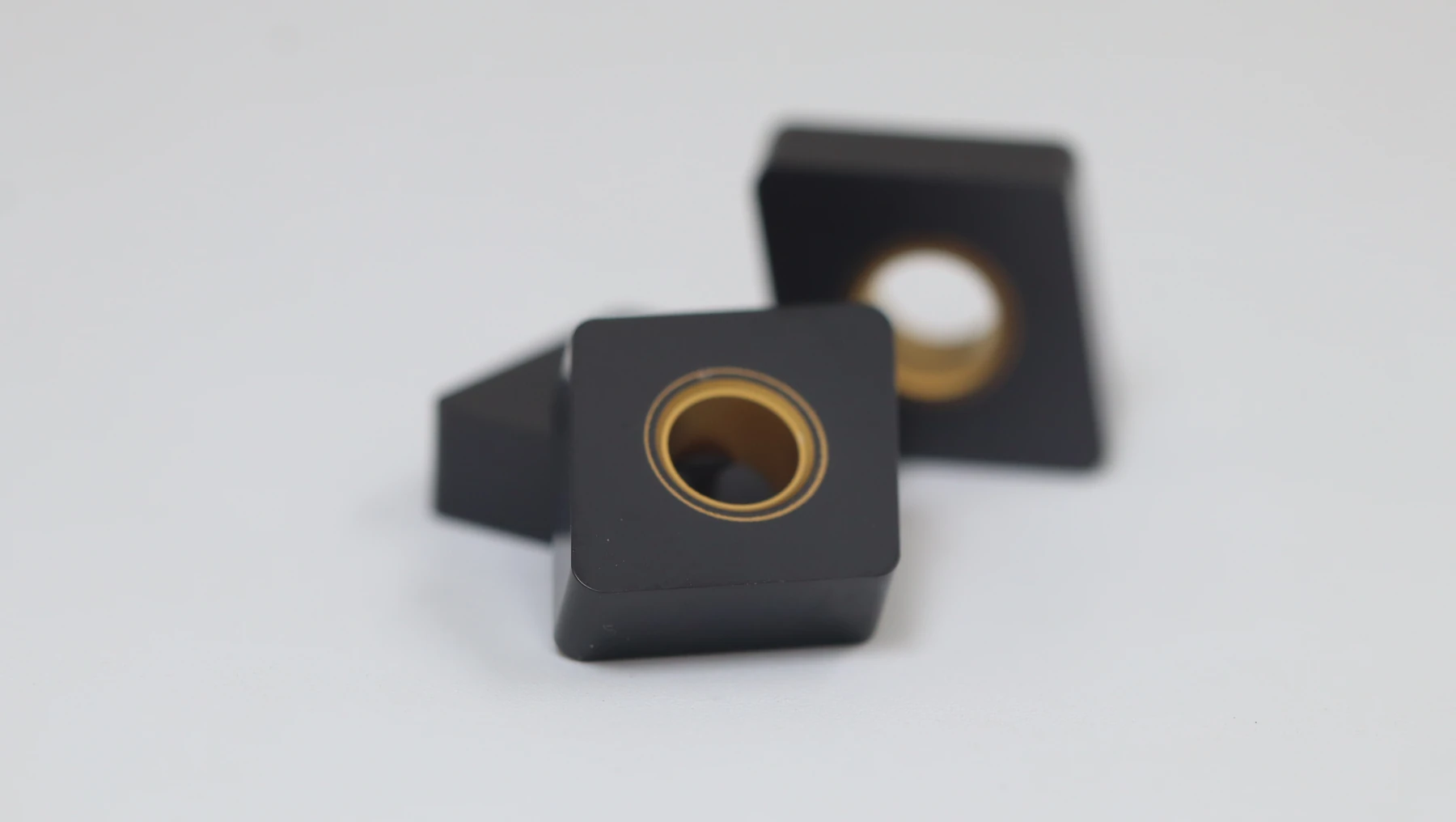 A gold and grey triangular turning insert leaning on its box, the label reading TNMG160408 TM MD9116