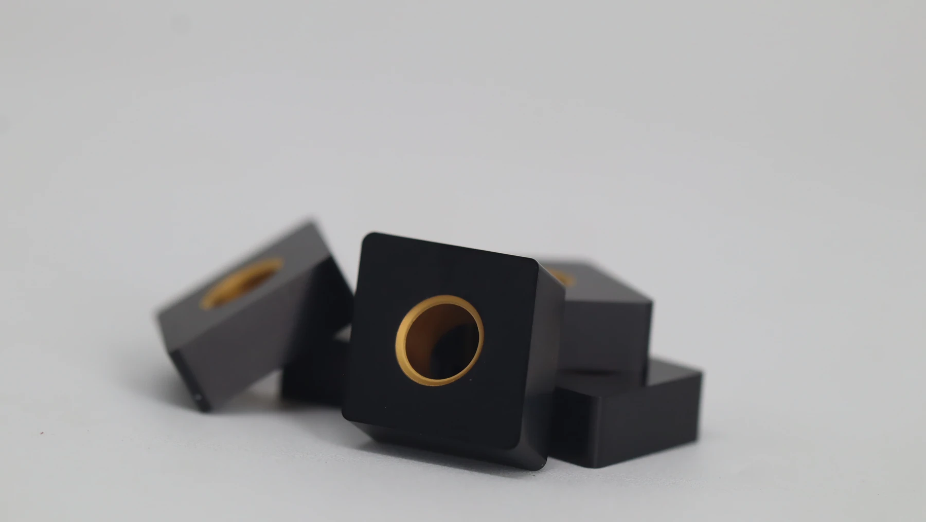 Three maroon-coated milling inserts laid in front of their open box