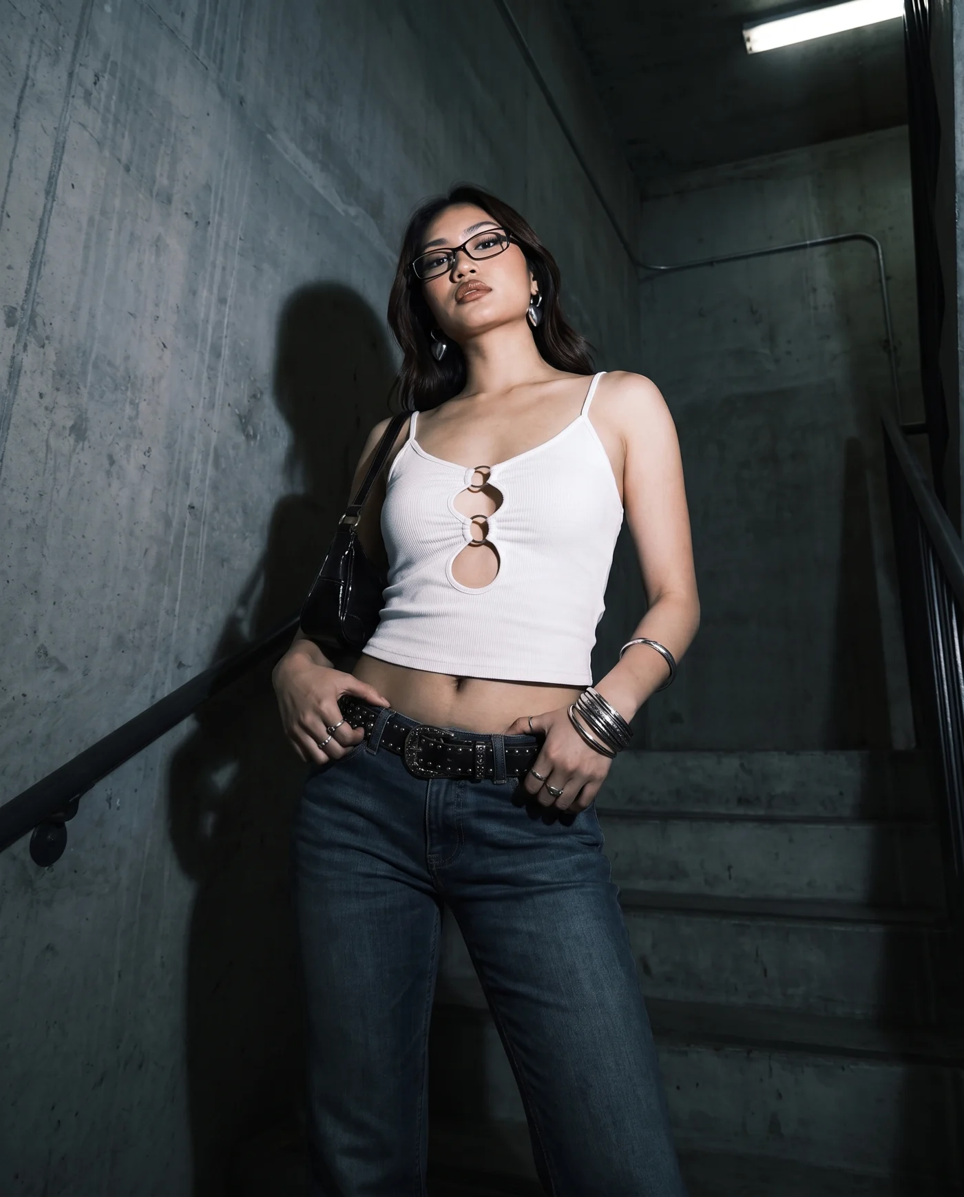 Casuall white cut-out top — against a concrete stairwell wall under a hard overhead strip light