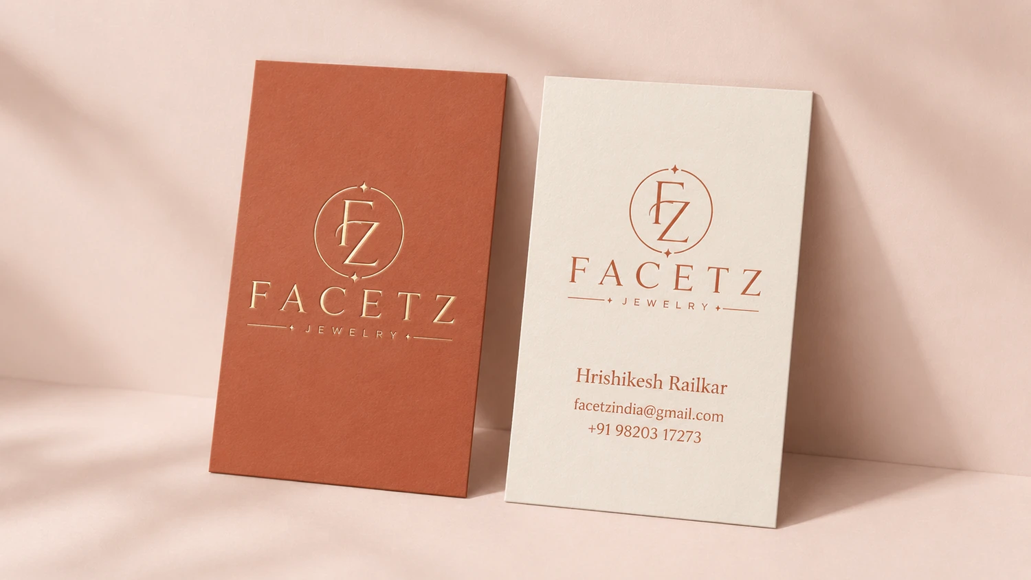 FACETZ stationery — business cards in terracotta and off-white with the foil monogram