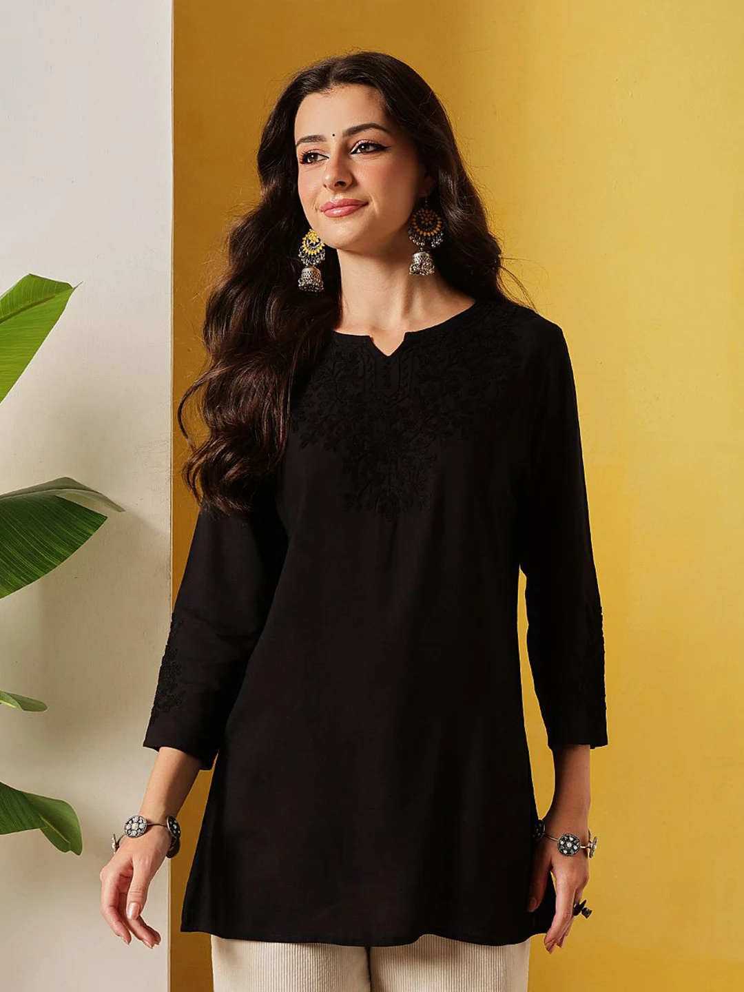 A FEMBLISS plain black tunic against a yellow ground