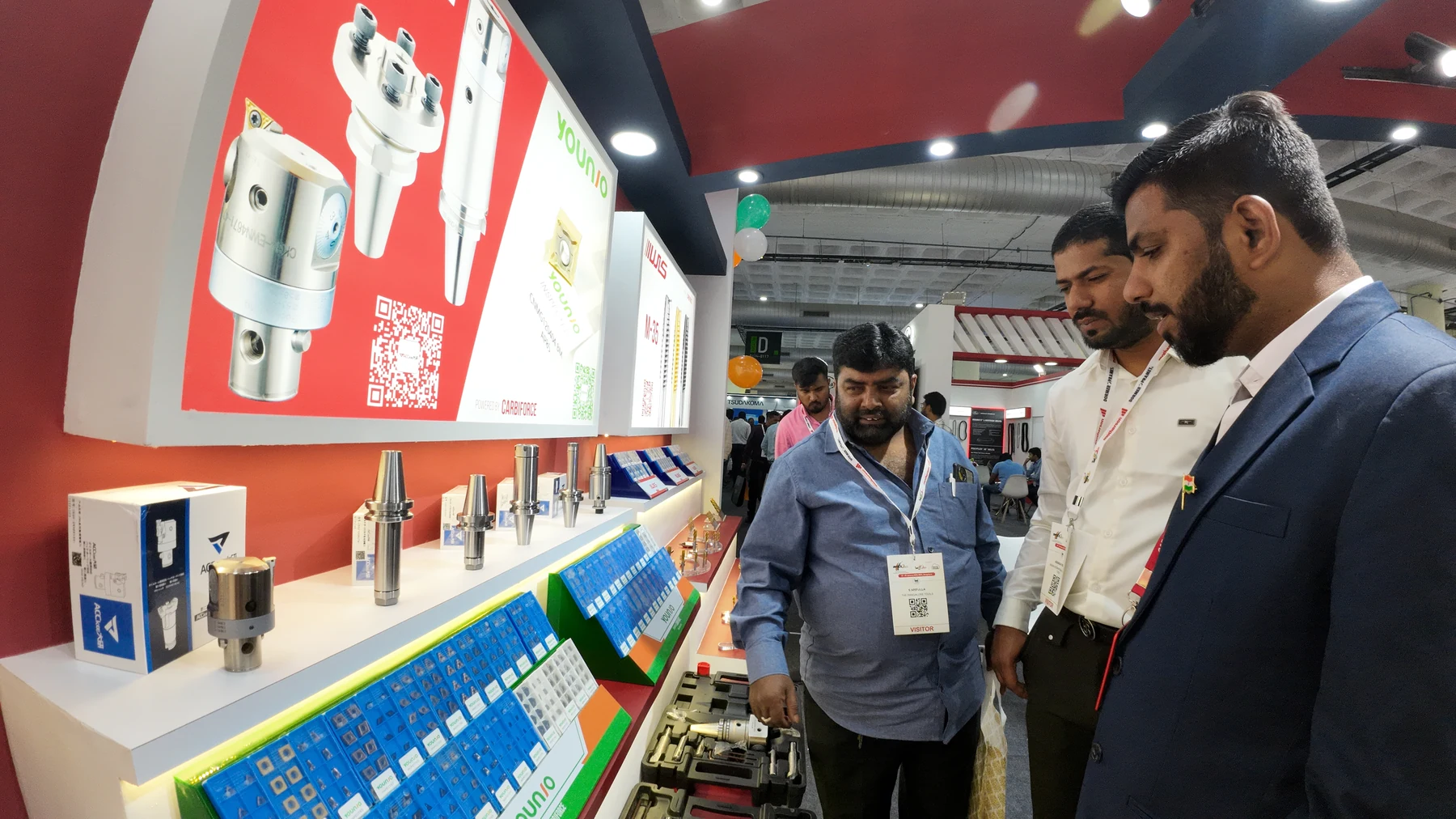Visitors leaning over a lit display case of drills and tool holders