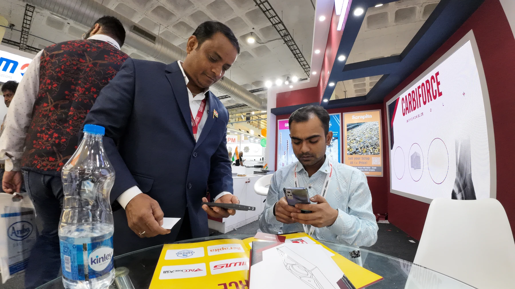 A business card passing between two people over a glass table on the stand